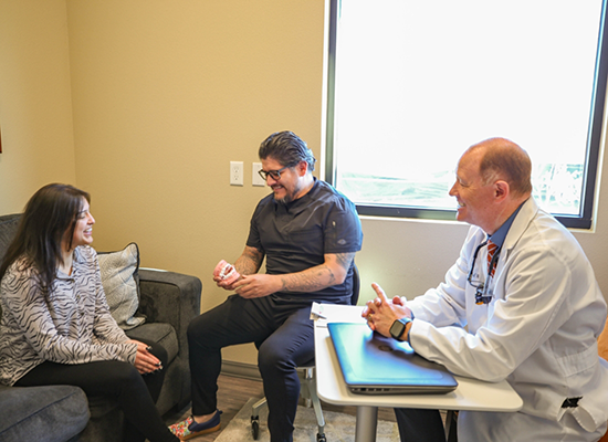 Dr. Waite sitting at table talking with two patients