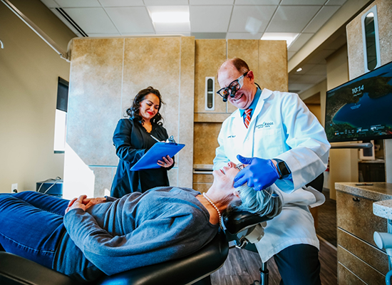 Colorado Springs dentist examining patient with magnifying glasses