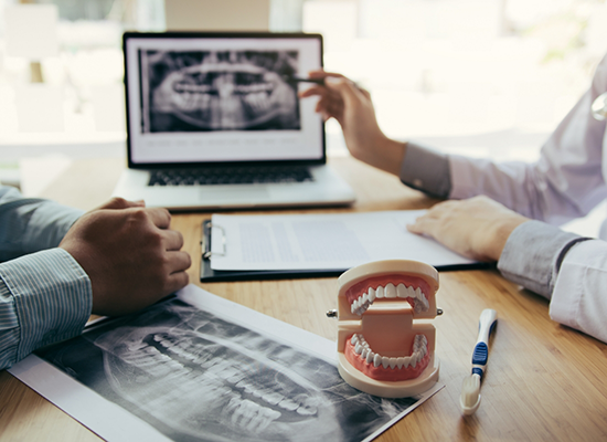 Sitting at dentist's desk discussing a dental X-ray