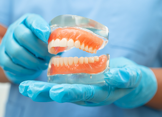 Dentist holding full dentures embedded in clear material