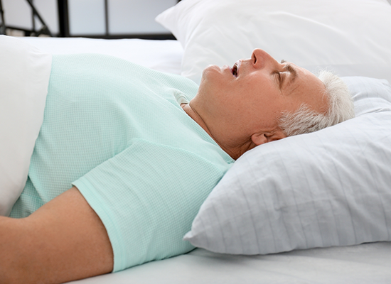Close up of older person snoring in bed