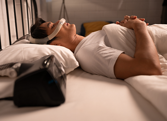 Man in bed with CPAP machine for sleep apnea treatment in Colorado Springs
